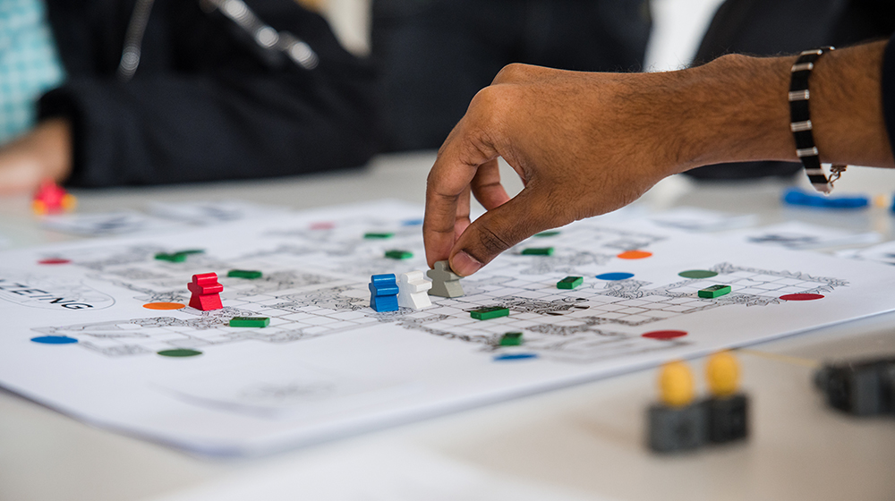 Nahaufnahme von einer Hand, die eine Figur auf einem Spielplan setzt (c) Jana Dünnhaupt Uni Magdeburg